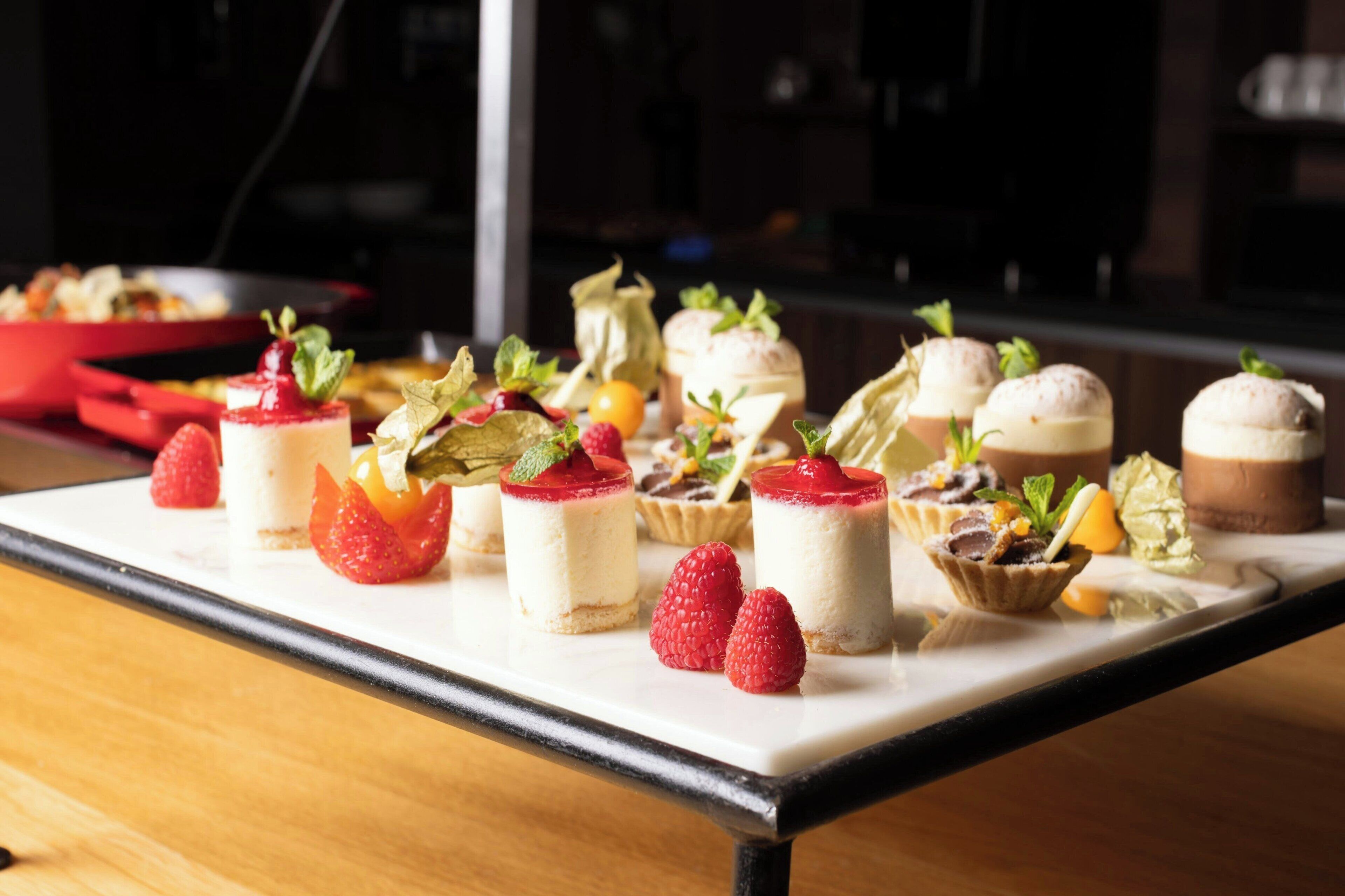 Un plateau de desserts comprenant divers petits desserts et des fraises fraîches, le tout disposé sur une table blanche.