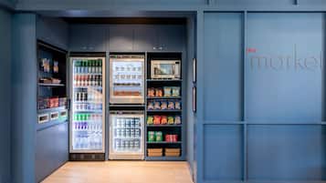 Um espaço comercial moderno com dispensadores de bebidas refrigeradas, prateleiras de lanches e um micro-ondas.