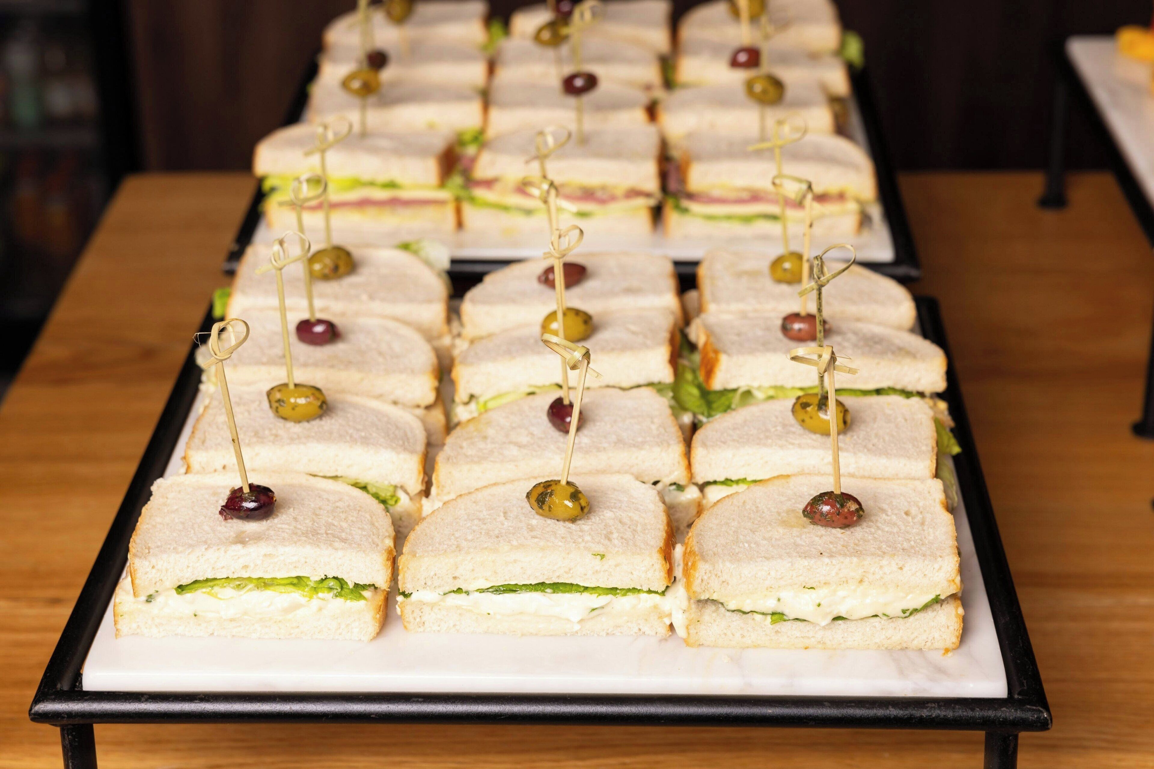 A tray of sandwiches with toothpicks, arranged on a table.