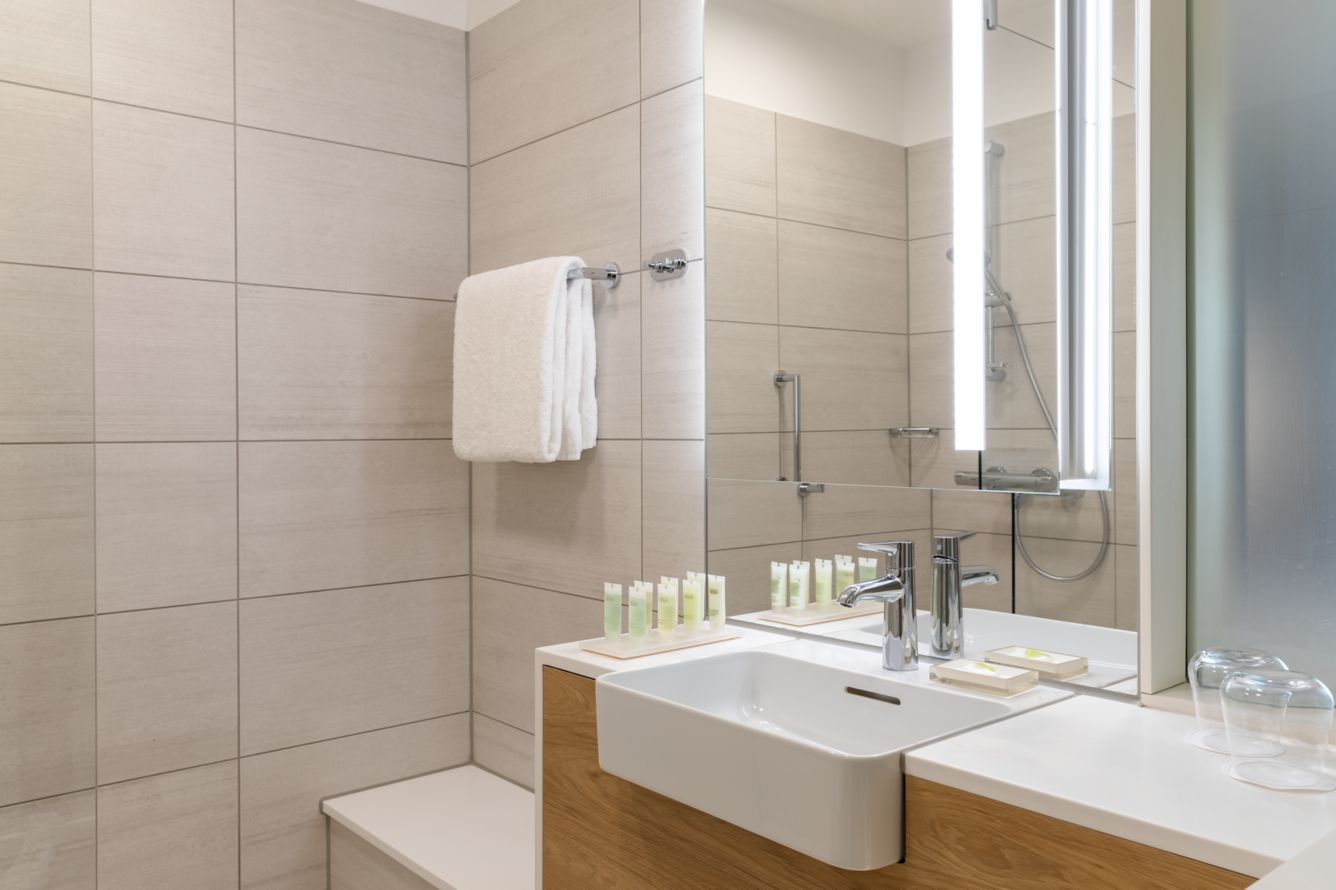 A modern bathroom with a large mirror, a sink, and a shower.