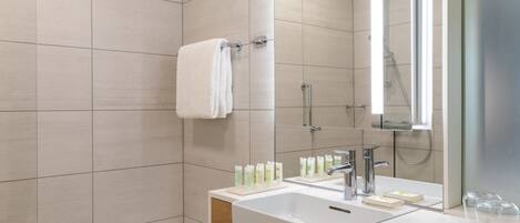 Un baño moderno con un espejo grande, un lavamanos y una ducha.