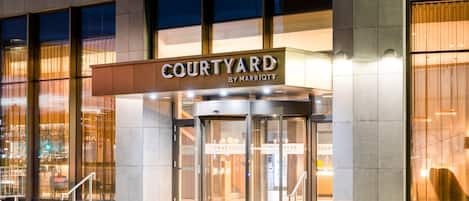 Ein Hotel Eingang mit einer Drehtür und einem Schild mit der Aufschrift 'Courtyard by Marriott'.