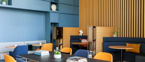 A modern meeting room with a black table, blue and orange chairs, a blue sofa, and a wooden accent wall.