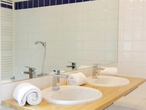 Een aparte badkuip en douche, een haardroger, handdoeken