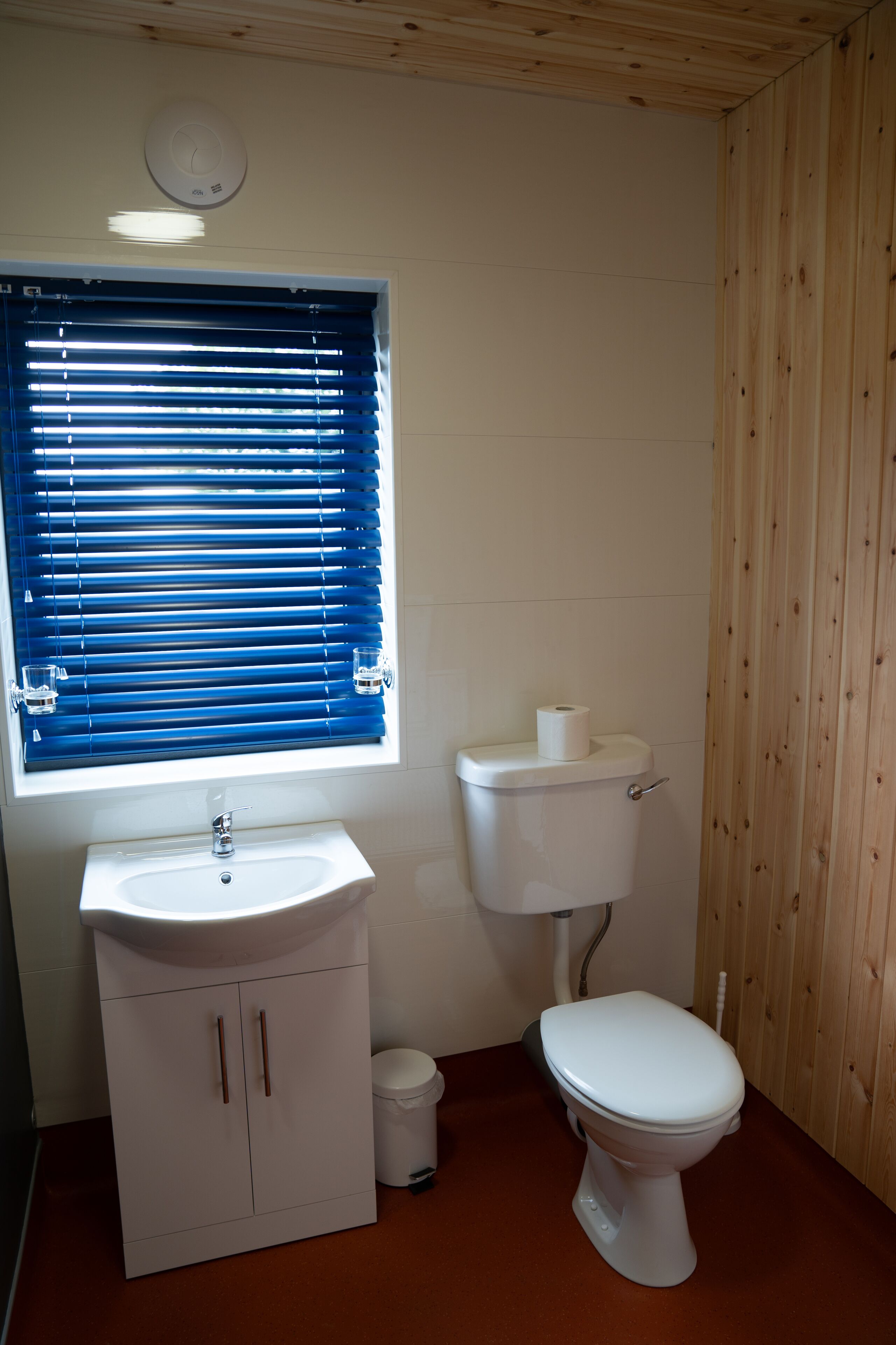 A bathroom with a white sink, toilet, and window with blue blinds.