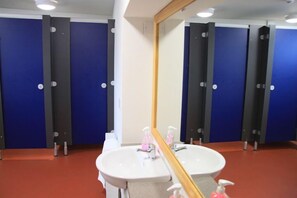 Un baño con cabinas azules, un lavamanos blanco y un espejo.