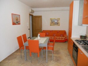 Une cuisine de taille réduite comprenant une table et des chaises, un canapé et une cuisinière.