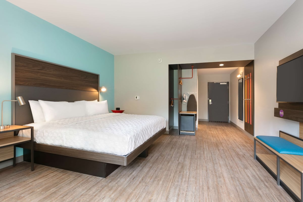 Una habitación de hotel moderna con una cama grande, mesitas de noche, un escritorio y un televisor.