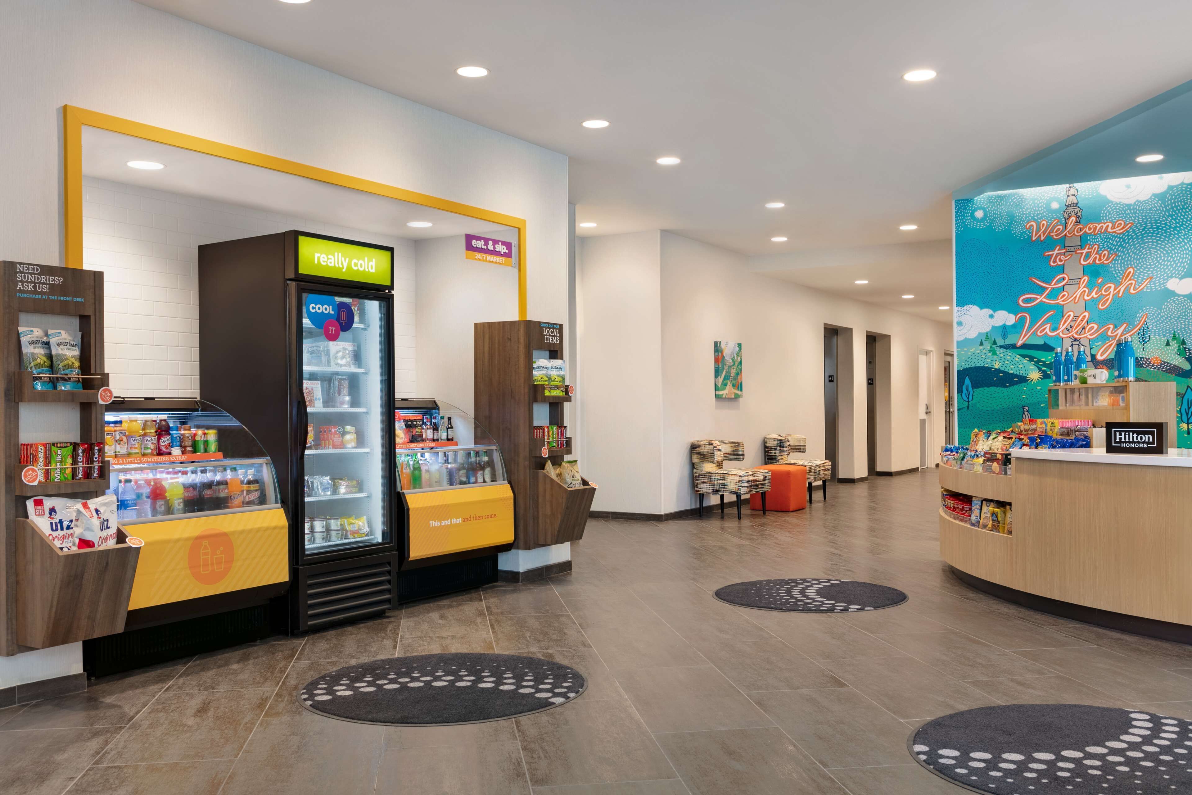 A hotel lobby with a 'really cold' beverage machine, a 'cool it' sign, and a 'Welcome to the Lehigh Valley' mural.