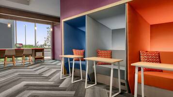 A modern lounge area with seating and tables, large windows, and a herringbone carpet pattern.