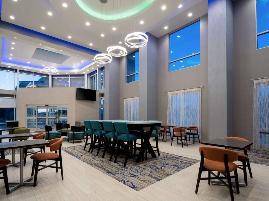 Un hall de hotel espacioso con varias zonas de estar, amplias ventanas e iluminación moderna.