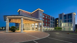 A modern hotel with a covered entrance, multiple floors, and a well-lit facade. - Hampton Inn & Suites Gilroy (Gilroy)
