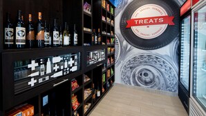 A store interior with shelves stocked with snacks and drinks, a large sign reading "TREATS", and a mural on the wall. - Hampton Inn & Suites Gilroy (Gilroy)
