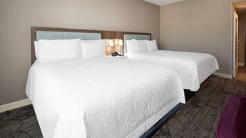 A hotel room with two beds, a nightstand with a phone, and a carpeted floor.