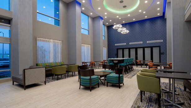 A spacious lobby with high ceilings, large windows, and a variety of seating arrangements including sofas, chairs, and tables. - Hampton Inn & Suites Gilroy (Gilroy)