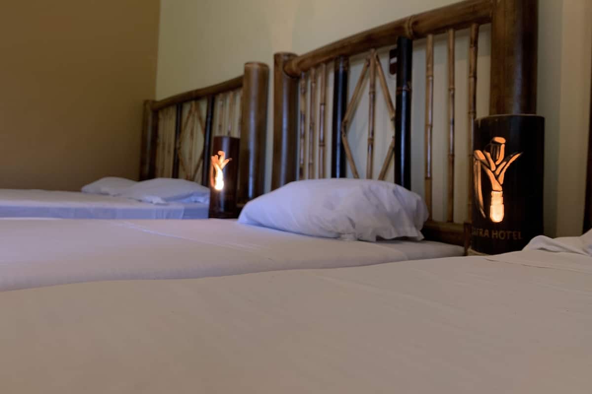A hotel room with two beds, a wooden headboard, and a nightstand with a lamp.