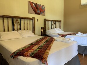 A hotel room with two beds, a decorative wall hanging, and a bedside table with a phone. - Zafra Hotel (San Martín Zapotitlán)