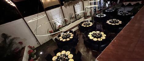 A restaurant with multiple round tables, each set with plates and cutlery.