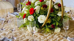 A table set for a formal event with a floral centerpiece, gold decorative arches, and a festive background. - Zafra Hotel (San Martín Zapotitlán)