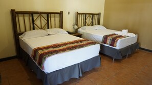 Two single beds with wooden headboards, white linens, and colorful blankets. - Zafra Hotel (San Martín Zapotitlán)