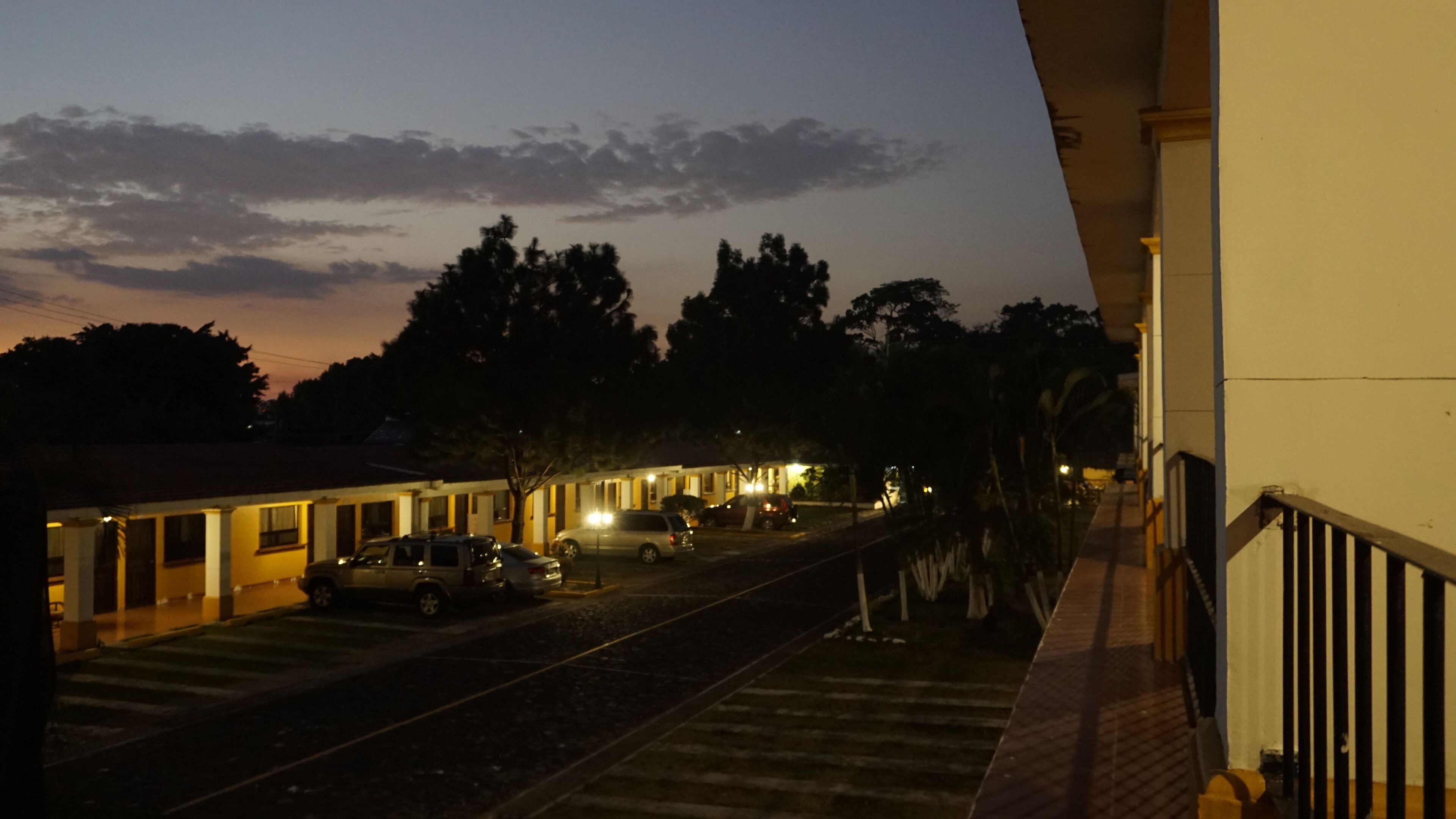 A motel with a row of rooms, a parking area, and a train track.