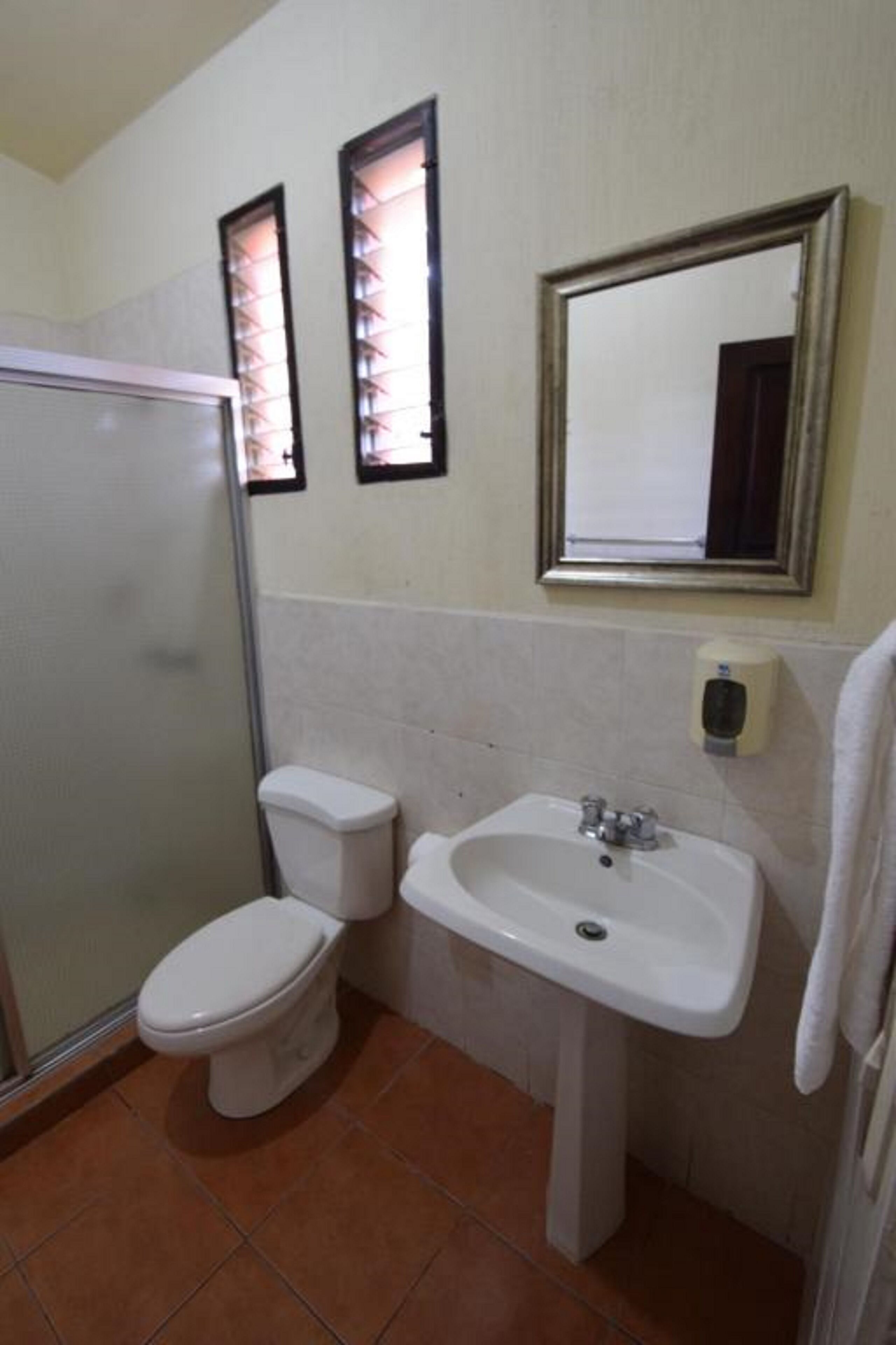 A bathroom with a toilet, sink, and a shower.
