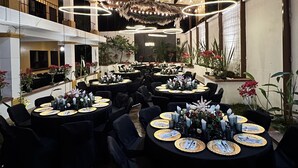 A spacious indoor dining area with multiple round tables set for guests, featuring black chairs and gold-rimmed plates. - Zafra Hotel (San Martín Zapotitlán)