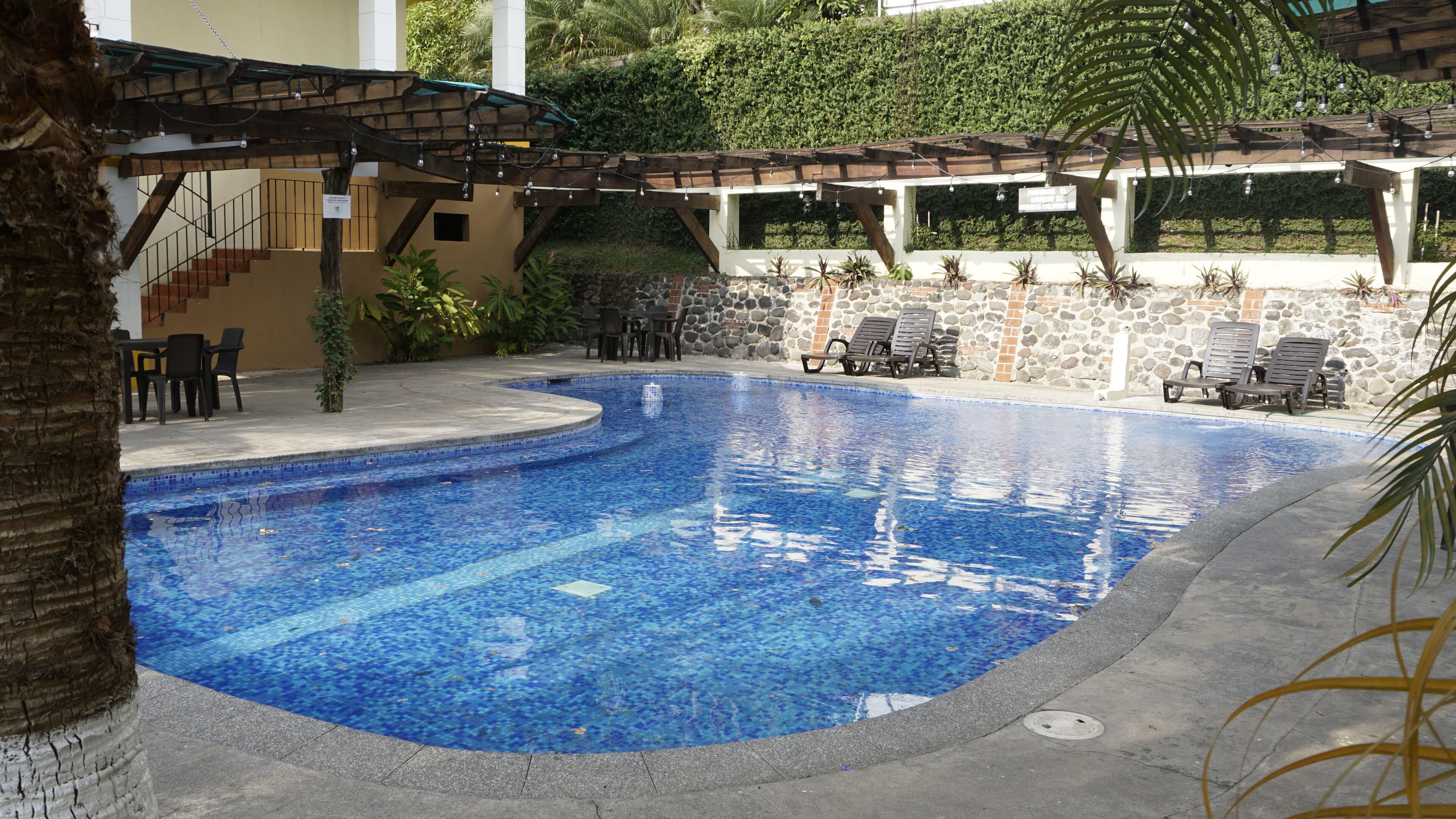 A swimming pool with lounge chairs and a pergola.
