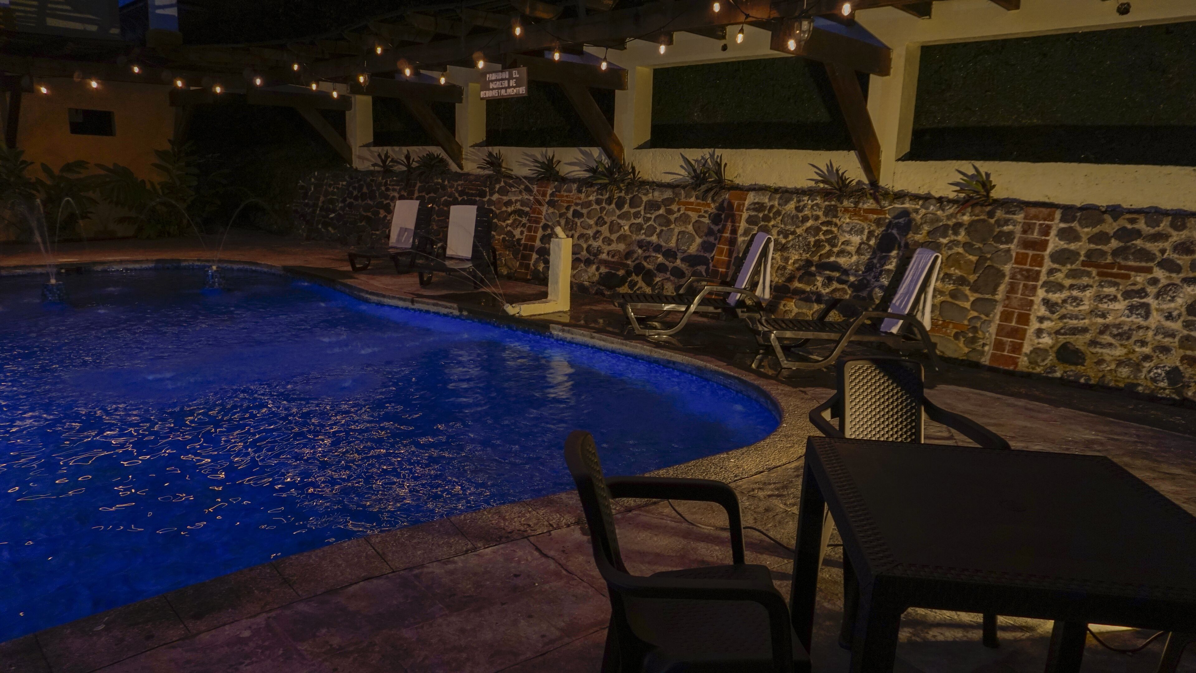 An outdoor swimming pool with lounge chairs and a stone wall.