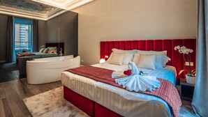 A modern hotel room with a large bed, a separate seating area with a sofa and a small table, and a decorative ceiling. - Growel Exclusive Suites San Pietro (Rome)