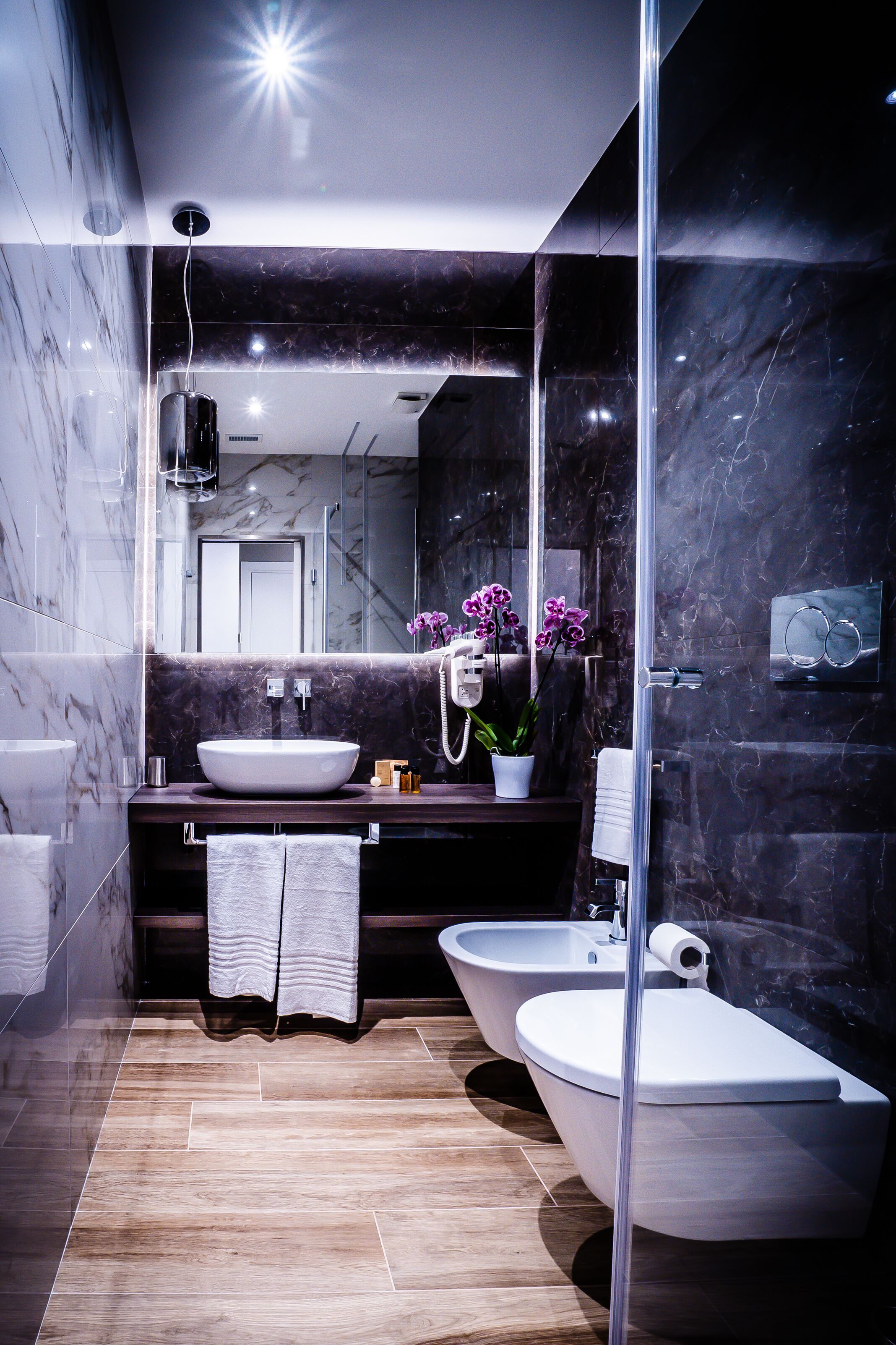 Un bagno moderno con uno specchio grande, un lavandino bianco, una vasca da bagno e un water.