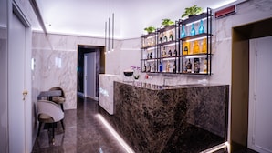 A modern bar area with marble countertops, a black marble island, and shelves with bottles. - Growel Exclusive Suites San Pietro (Rome)