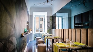 A restaurant with multiple tables set for dining, a bar area, and a view of the street. - Growel Exclusive Suites San Pietro (Rome)