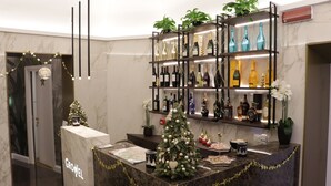 A reception area with a marble counter, a Christmas tree, and shelves of liquor bottles. - Growel Exclusive Suites San Pietro (Rome)