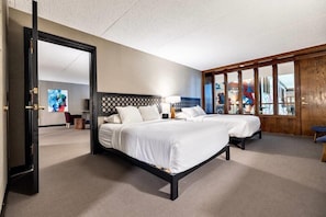 A hotel room with two beds, a large mirror, and a view of the cityscape. - The Bohemian (Iowa City)