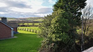 A rural landscape with a grassy yard, a brick building, and a large tree. - This well-equipped cottage is perfect for a family or group holiday. (Hinderwell, near Whitby)