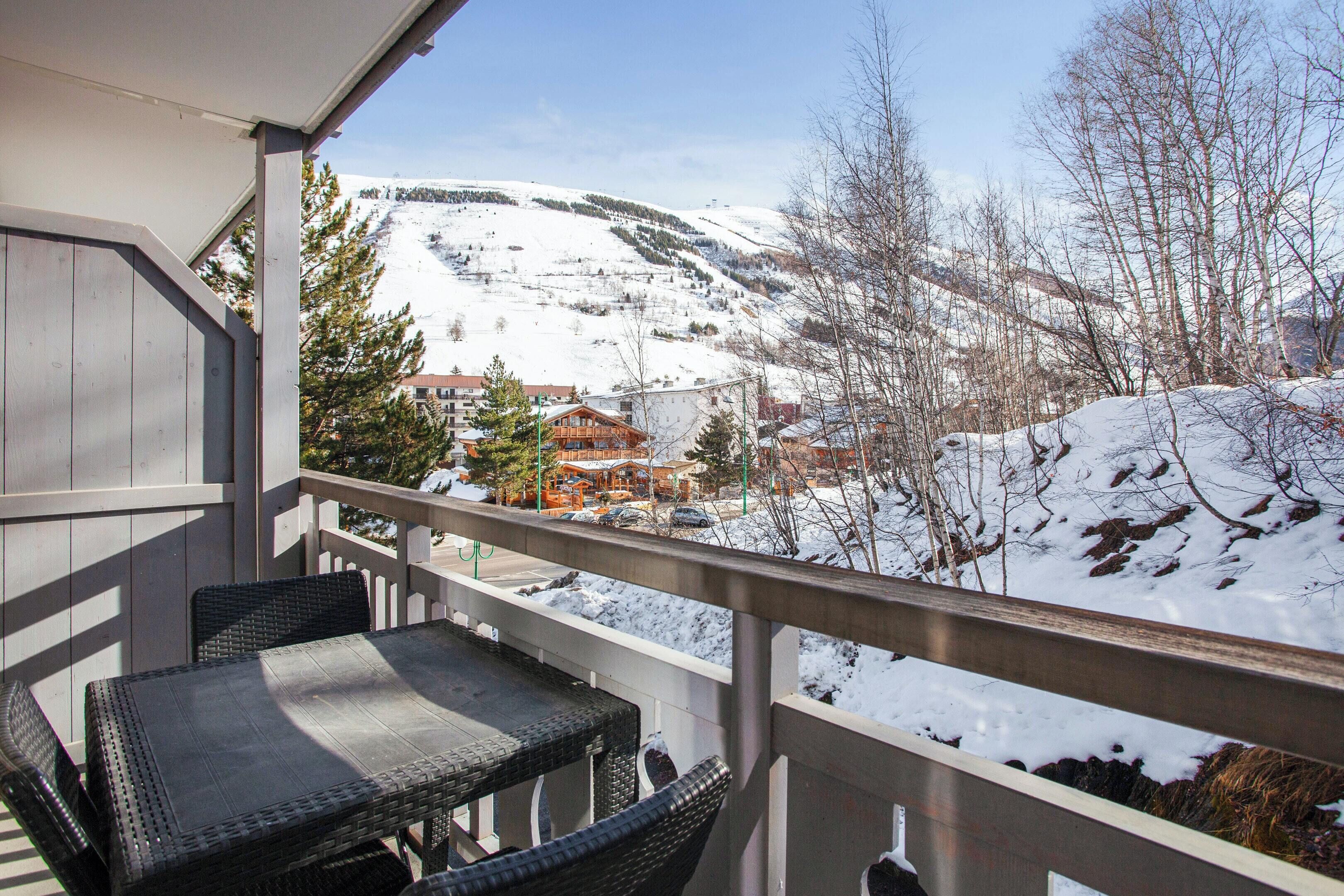 Un balcon doté de meubles en osier, offrant une vue sur un paysage montagneux enneigé.