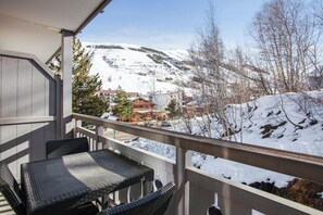 Un balcon doté de meubles en osier, offrant une vue sur un paysage montagneux enneigé.