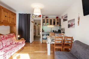 A cozy living room with a sofa and a dining table with chairs.