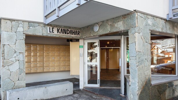 Un edificio con facciata in pietra, una cassetta delle lettere e una porta con su scritto "LE KANDAHAR".