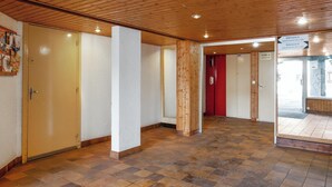 Un corridoio con soffitto in legno e pavimento piastrellato, che conduce a diverse porte.