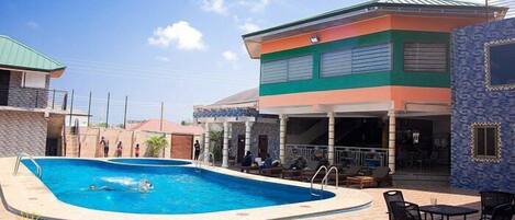 Zona de piscina con sillones de descanso y una zona de estar cubierta.