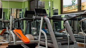 A gym with treadmills and weight machines, a mirror, and a window with the Hotel Green logo. - Hotel Green (Accra)