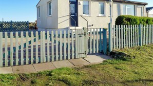 A two-story house with a white exterior, a front door, and a small porch. - 2 bedroom accommodation in Southerness, near Dumfries (Southerness, near Dumfries)
