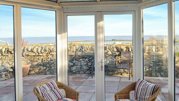 A conservatory with wicker furniture and a view of the sea through stone walls. - 2 bedroom accommodation in Southerness, near Dumfries (Southerness, near Dumfries)
