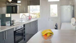 A modern kitchen with a central island, a built-in oven, and a refrigerator. - 2 bedroom accommodation in Southerness, near Dumfries (Southerness, near Dumfries)
