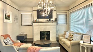 A living room with a fireplace, a sofa, a coffee table, and a TV mounted on the wall. - Southern Staycation! (Greenville)