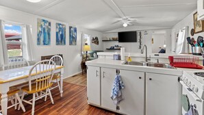 A compact kitchen with a dining area, white cabinetry, a built-in oven, and a television on the wall.