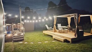 An outdoor patio area with a wooden deck, seating, and string lights.