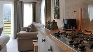 Una cocina moderna con estufa a gas, cafetera y vista a un jardín por la ventana.